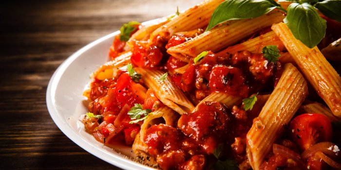 pasta with meat, tomato sauce and vegetables on white background