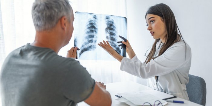 young doctor talking to a patient in her cabin doctor showing x-ray to patient doctor and patient looking at xray in medi...
