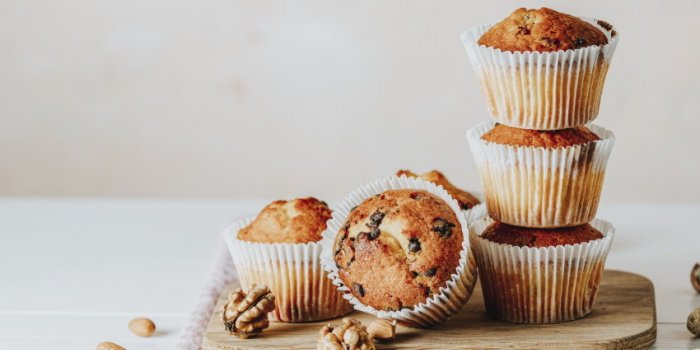vanilla caramel muffins in paper cups on white wooden background delicious cupcake with raisins, almonds and nuts homemad...