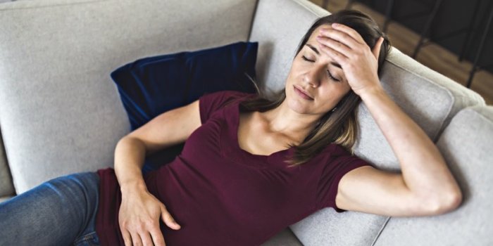 a sick woman lying on sofa in the living room with stomach ache