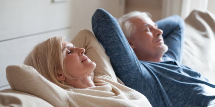 calm senior mature couple relaxing on soft comfortable sofa having daytime nap together, carefree middle aged old family ...