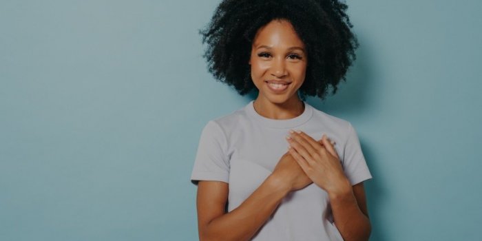 grateful hopeful happy black woman holding hands on chest, satisfied and sincere african lady expressing love from heart,...