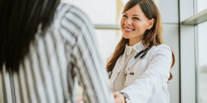 female doctor talking and touching woman patient for encouragement