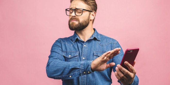 young handsome business man talking on the phone over pink isolated background with open hand doing stop sign with seriou...