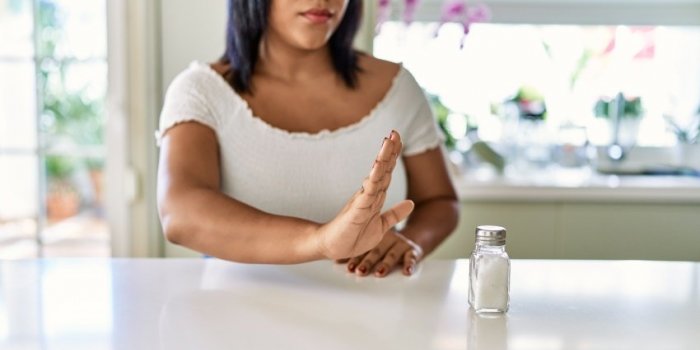 hispanic brunette woman rejecting salt at the kitchen