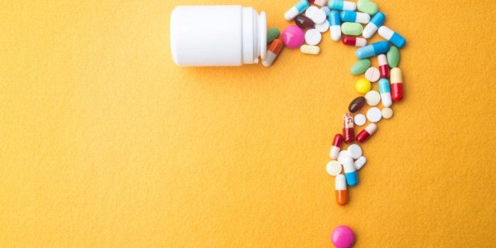 pills or capsules as a question mark and white plastic bottle