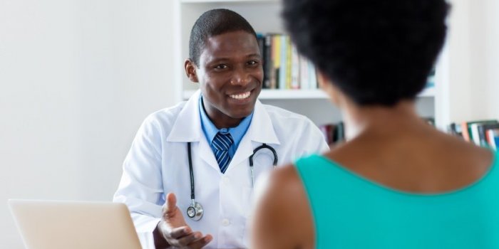 african american doctor with good news for female patient at hospital