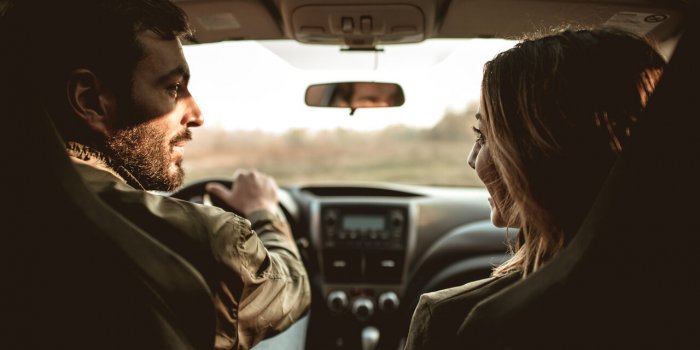 happy couple in a car looking at each other back view
