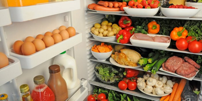 open door of fridge with shelves filled with fresh food produce