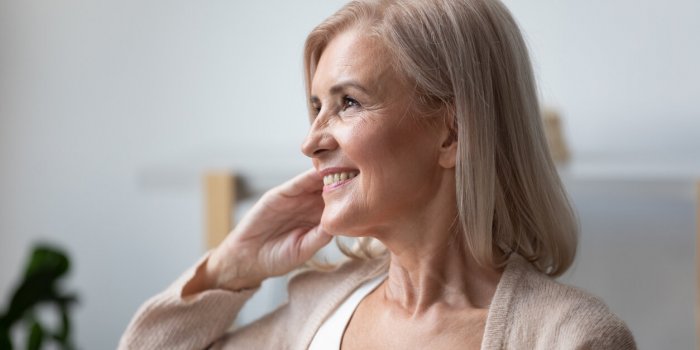close up of positive elderly female pensioner sit relax at home look in distance window dreaming or visualizing, smiling ...