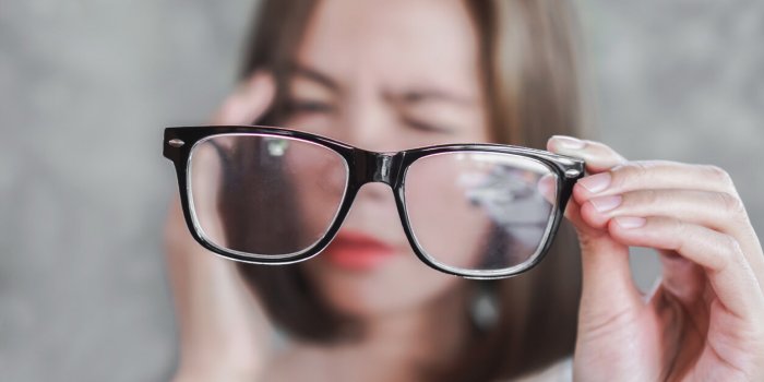 asian woman holding eyeglasses having headache from eye blur vision