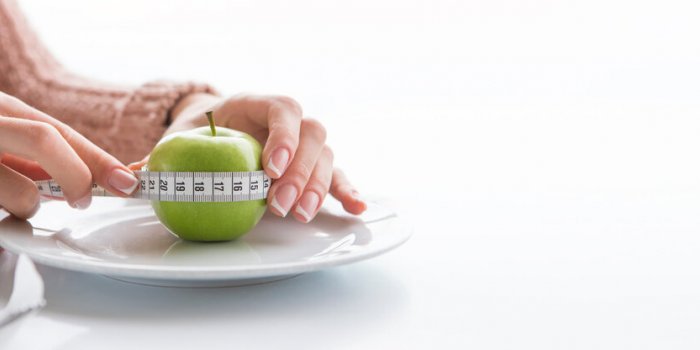 woman measures the circumference of the apple with tape measure