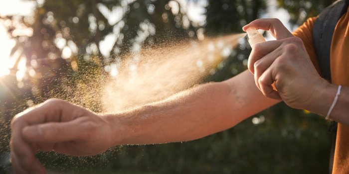 man is applying insect repellent on his hand against palm trees prevention against mosquito bite in tropical destination