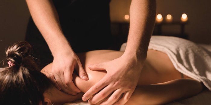 close up male manual worker doing spa massage to a young girl in a dark room