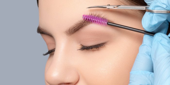 makeup artist comb and trim the eyebrows with scissorss to a woman before staining with henna women's cosmetology in the ...