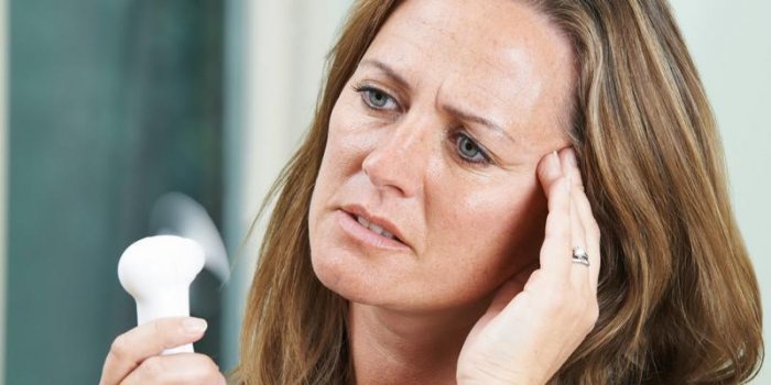 femme mature éprouvant une bouffée de chaleur de la ménopause