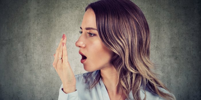 woman checking her breath with hand