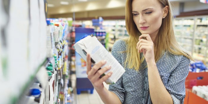 young woman reading label milk