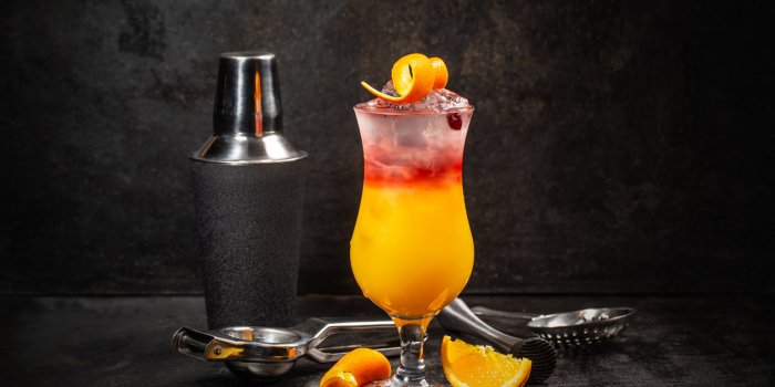 glass of sex on the beach cocktail and shaker against dark background