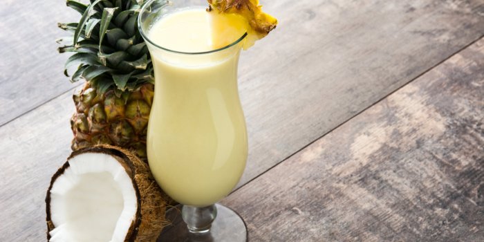 piña colada cocktail and pineapple fruit on wooden background
