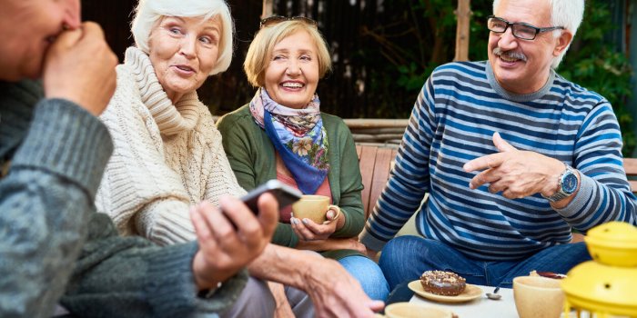group of cheerful seniors enjoying time together drinking tea outdoors in cafe and sharing life stories in retirement