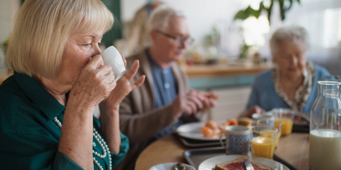 a group of cheerful seniors enjoying breakfast in nursing home care center