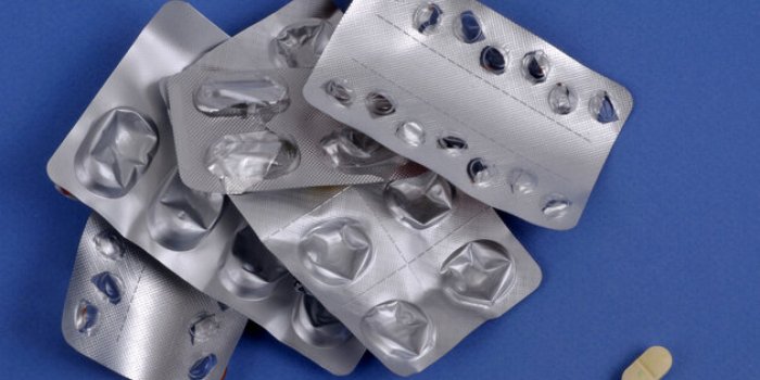 medicine shortage concept with a pill and empty blister packs close up on a blue background