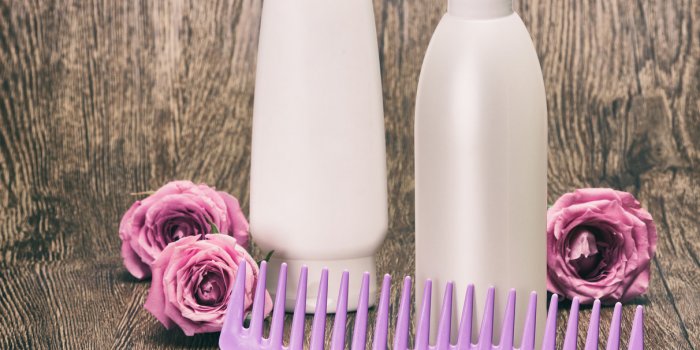 hair care and styling cosmetics for women hair beauty products and wide tooth comb with roses on wooden surface toned ima...