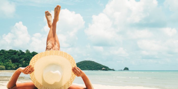 girl lies on the white sand on the beach woman tanning relaxing on beach female adult from the back lying down with straw...