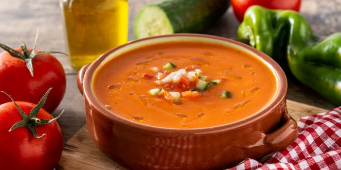 gazpacho soup in crock pot and ingredient on wooden table