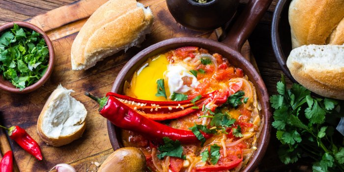 chilean food picante caliente or spicy hot with onion, tomatos, chilli aand eggs in tipicacal chilleann cllay pan