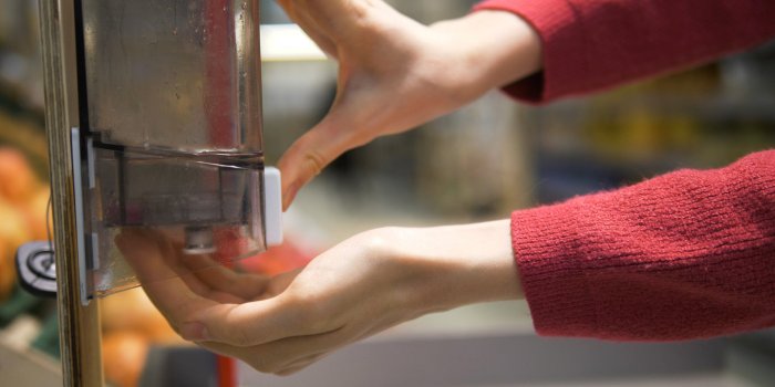 woman's hands close-up disinfects her hands with a sanitizer in a grocery supermarket protection from the coronavirus pan...
