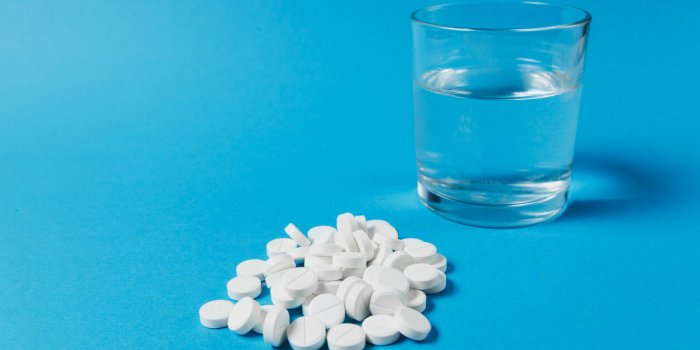 medication pile white round tablets arranged abstract on blue color background aspirin, glass water pills for design heal...