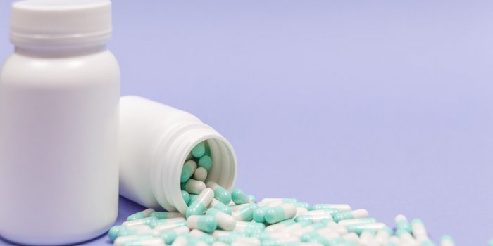 blue and white capsules pill spilled out from white plastic bottle container global healthcare concept antibiotics drug r...