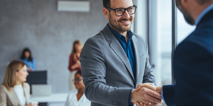 portrait of cheerful young manager handshake with new employee business partnership meeting in office close up of handsha...