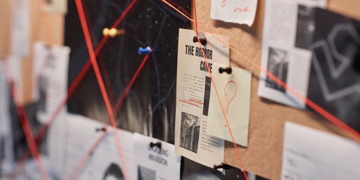 closeup background image of evidence board with red thread connecting pictures, copy space