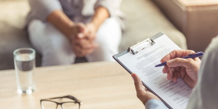 cropped image of depressed man at the psychotherapist doctor is making notes while listening to his patient