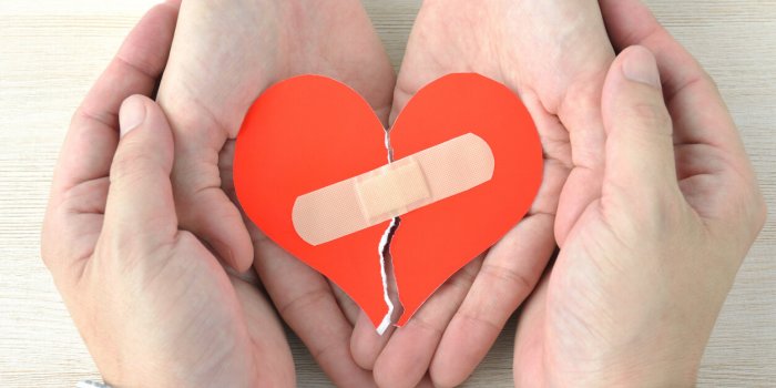 couple's hands having broken heart with adhesive plaster