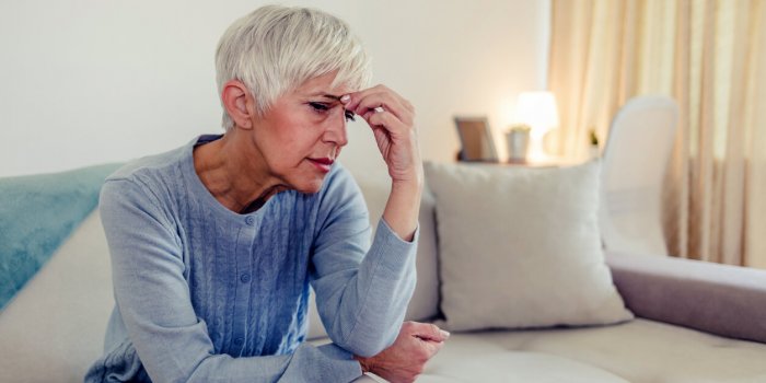 photo of woman suffering from stress or a headache grimacing in pain as she holds forehead with her hand, with copy space...