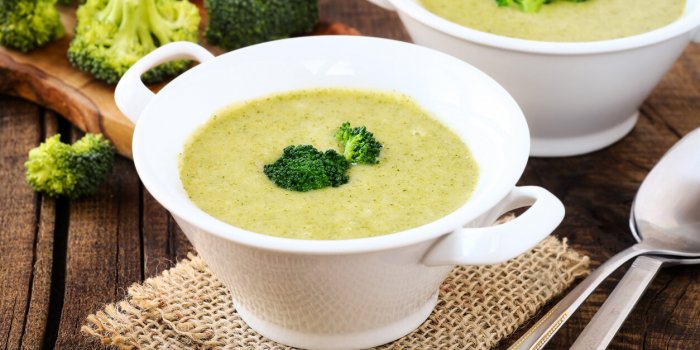healthy vegetarian cream of broccoli soup in white bowls on a rustic kitchen table