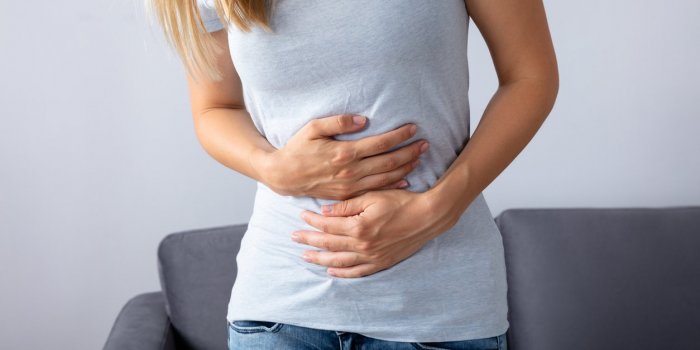 woman sitting on sofa suffering from stomach pain