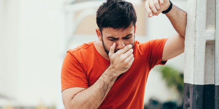 portrait of young man drunk or sick vomiting outdoors
