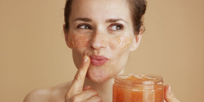 happy modern middle aged woman with face scrub on beige background