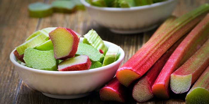 fresh rhubarb in white bowl on wooden table