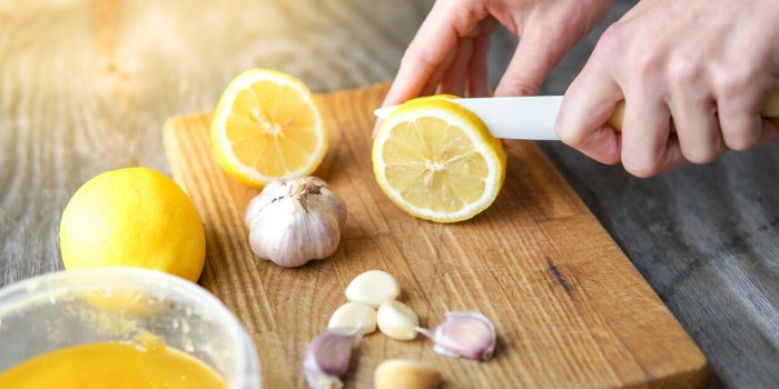 alternative medicine with lemon, garlic and honey over rustic background woman prepare healthy treatment