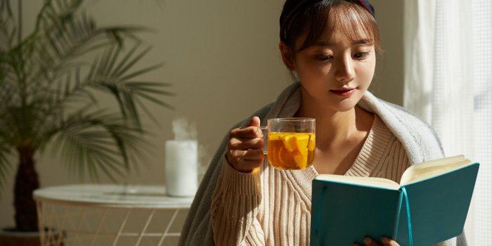 a young asian woman relaxing at home drinking fruit tea