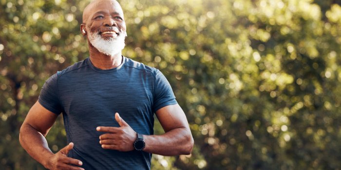 happy black man running in park with music, smile and mockup in nature, garden and workout senior male, outdoor runner an...