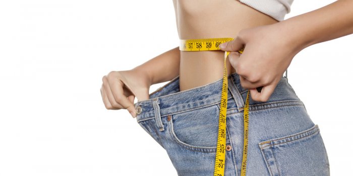 woman posing with a measuring tape and a big size pants