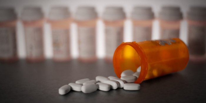 prescription medication is strewn about, with pill bottles in the deep background