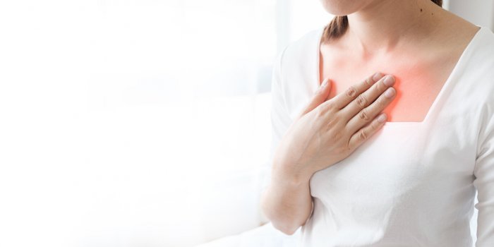young woman putting her hand on her chest having a pain in chest, gastroesophageal reflux disease have frequent belching ...